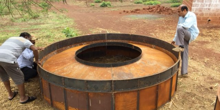 Three men in India, working on a biogas digester to produce clean fuel for cooking