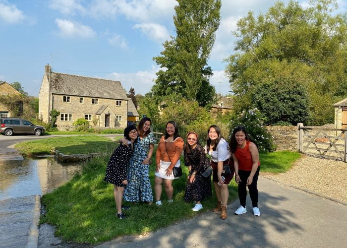 A group of American tourists enjoying the natural beauty of the ford at Upper Slaughter, in the Cotswolds