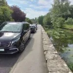 One of Rosehill Travel's electric cars parked by the river in Bibury