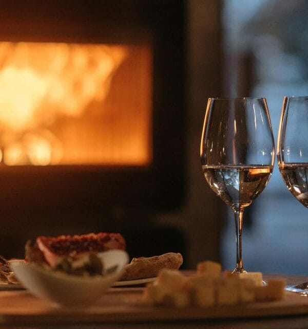 Two glasses of wine in front of an open fire accompanied by small snacks