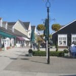 2025-11-18 Luxury Christmas Shopping Header Bicester Village in the sun, showing the awnings over luxury brand shops